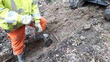 7. Willem steekt met de schep in de grond. Als hij niet op een kabel stuit, mag de graafmachine een laag weghalen.