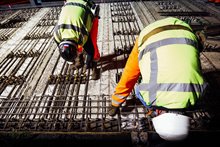 Op de tijdelijke brug wordt gaas gevlochten als voorbereiding op het storten van het beton.