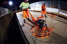 Het beton op de tijdelijke brug wordt uitgevlakt.